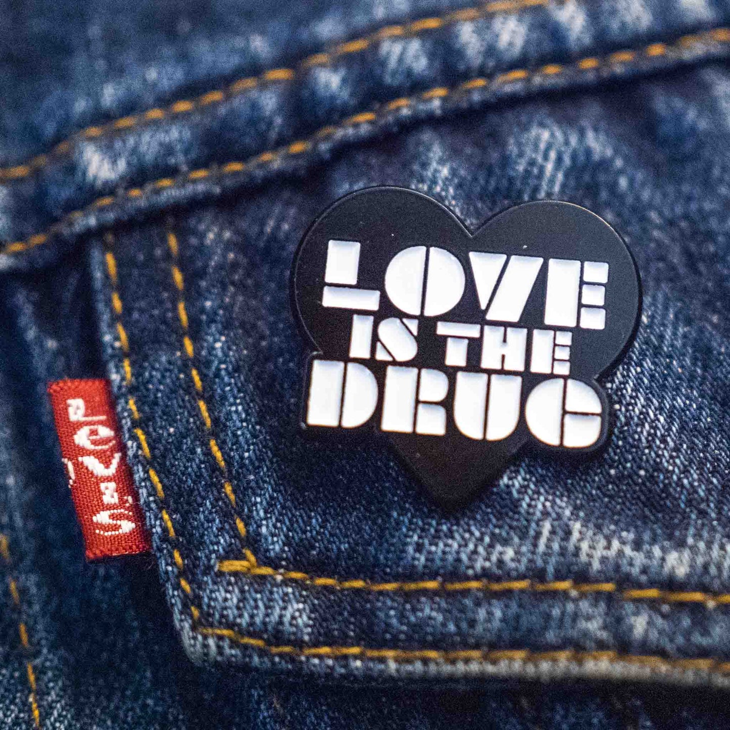 Black love is the drug pin badge in white enamel type on a denim jacket