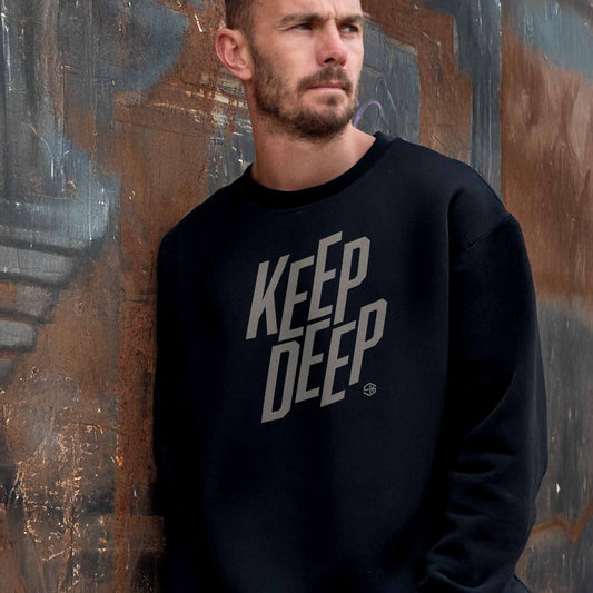 Man wearing a deep house black sweatshirt with 'KEEP DEEP' text against a textured wall.