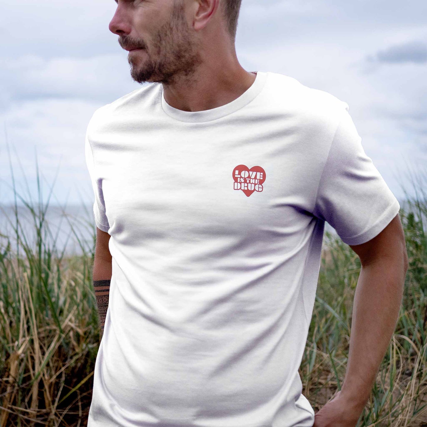 Man wearing Love is The Drug White T-shirt with Red Heart Design