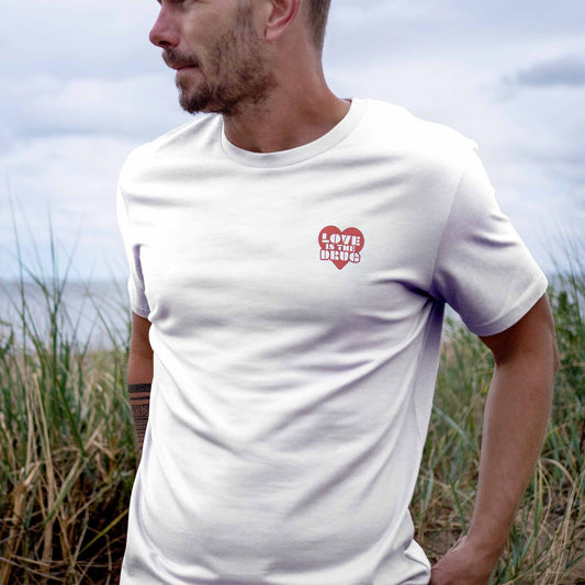 Man wearing Love is The Drug White T-shirt with Red Heart Design