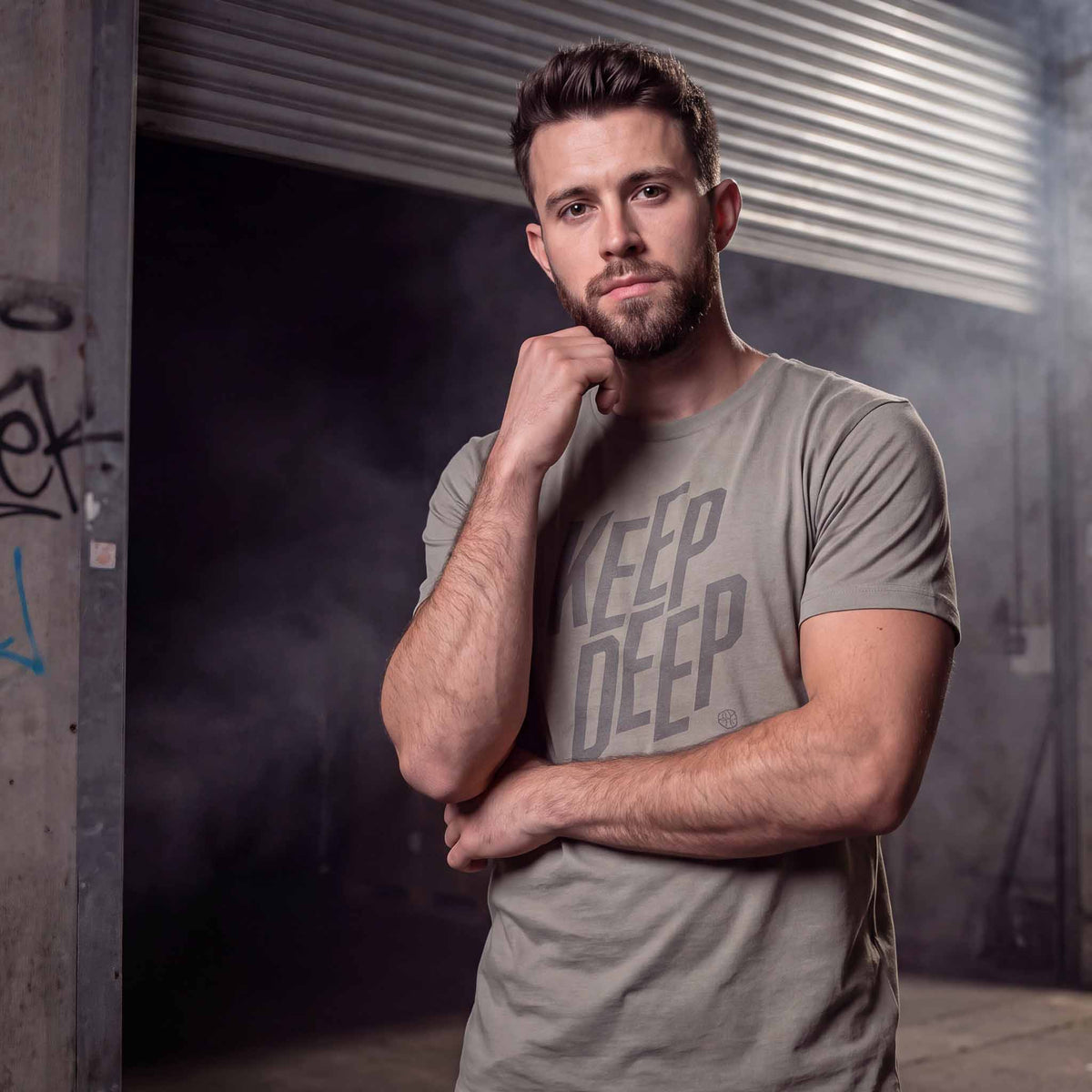 Man wearing a grey deep house t-shirt with 'KEEP DEEP' text in a warehouse