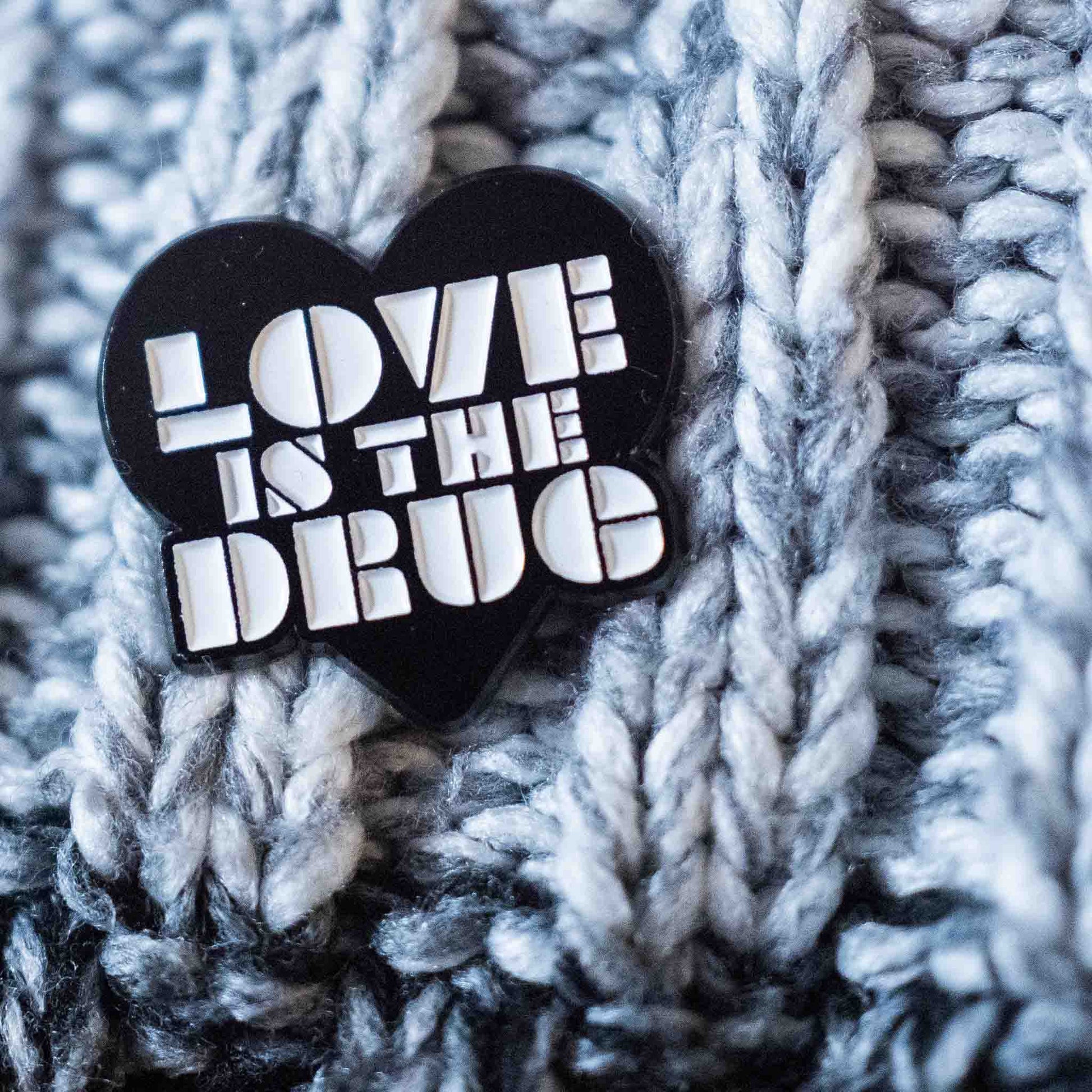 Black love is the drug pin badge in white enamel type on a wooly hat